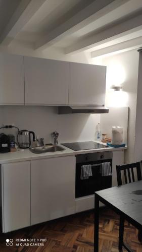 a kitchen with white cabinets and a sink and a table at Blue Windows in Camogli