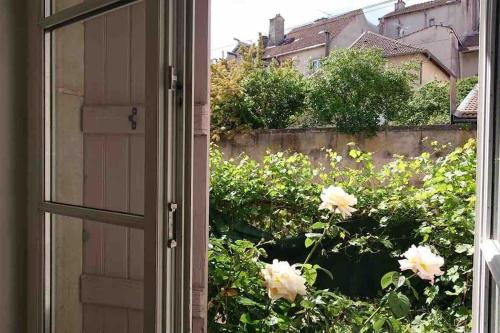 an open door to a garden with flowers outside at Logement au calme et en plein cœur ! in Neufchâteau