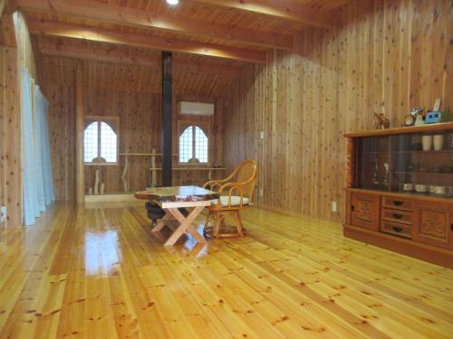 sala de estar con suelo de madera, mesa y sillas en 民泊くま - 絵画と音楽の宿 en Inawashiro