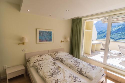 a bedroom with a bed and a large window at Haus Cristal - 1441m in Leukerbad