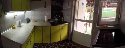 a kitchen with yellow cabinets and a window at Apartman Palić Libero in Palić