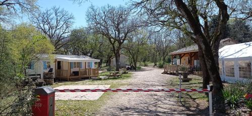 un groupe de cottages dans une forêt avec une clôture dans l'établissement CAMPING LE BEL AIR tente insolite Sibley's 4 personnes-LE ROMARIN, à Limogne-en-Quercy