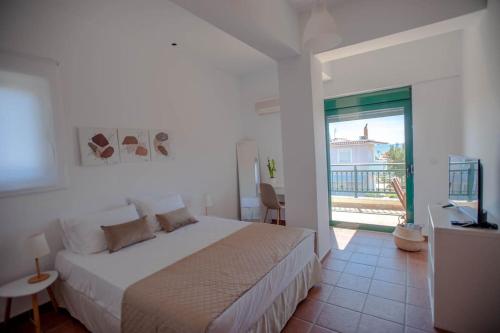 a white bedroom with a bed and a balcony at Villa Calliope Lardos in Lartos