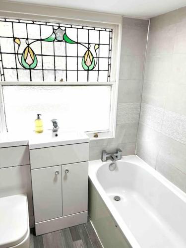 a bathroom with a tub and a toilet and a window at Bright & Relaxing Studio in Brighton & Hove in Brighton & Hove