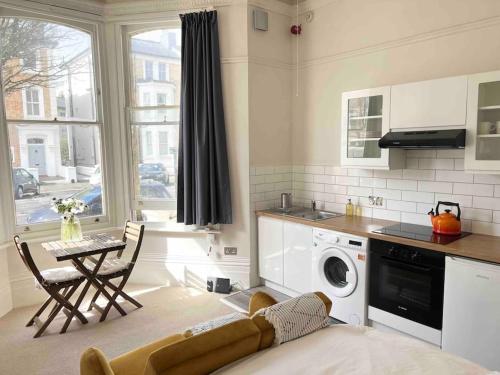 a kitchen with a table and a washing machine at Bright & Relaxing Studio in Brighton & Hove in Brighton & Hove