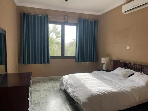 a bedroom with a large bed with blue curtains at Rose Guesthouse in Al ‘Aqar