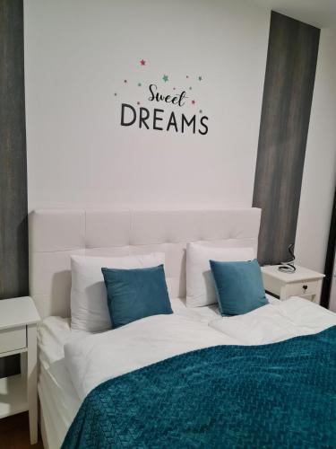 a white bed with blue pillows in a bedroom at Apartman Vinyl - self chek-in in Osijek