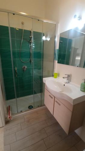 ein Badezimmer mit einem Waschbecken und einer Dusche mit einer Glastür in der Unterkunft S'Orgosa in Orgosolo