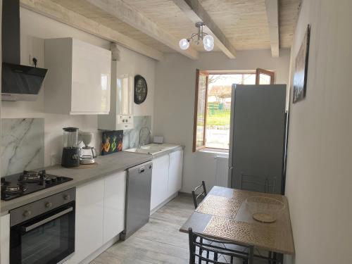 a kitchen with white cabinets and a table and a refrigerator at Les orchidées in Saint-Cybranet