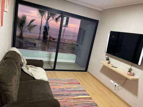 sala de estar con sofá y TV de pantalla plana en Departamento Nuevo con piscina frente al mar, en Lima