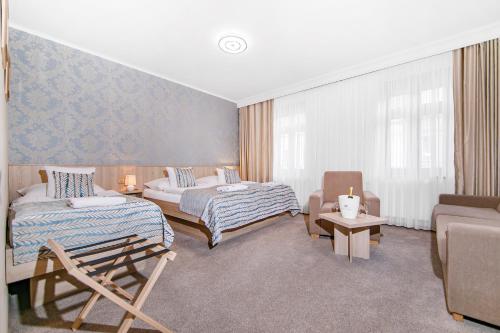 プルゼニにあるホテル ラウドナのベッドルーム1室(ベッド2台、椅子、ソファ付)