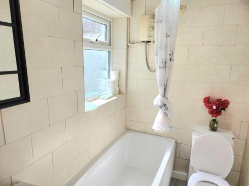 a bathroom with a tub and a toilet and a window at Hawkins Town House Near City Ctr and all Amenities in Liverpool