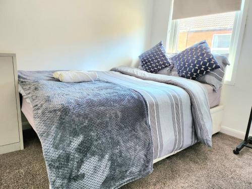 a bed with a blanket and pillows on it at Hawkins Town House Near City Ctr and all Amenities in Liverpool