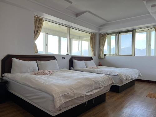 two beds in a room with large windows at Bokelai B&B in Renai