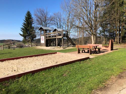 einen Park mit einem Spielplatz mit einer Bank und einer Rutsche in der Unterkunft Ferienwohnung Bergzeit mit Sauna und Pool in Sankt Englmar