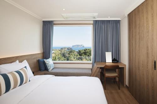 um quarto de hotel com uma cama e uma janela em Kensington Resort Seogwipo em Seogwipo