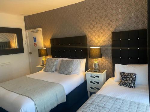 a hotel room with two beds and a night stand at Aaron in Southport