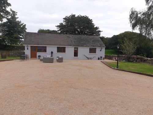 a white house with a large driveway in front of it at St Patrick's Cottage in Saul