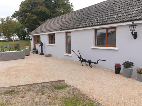 a white house with a bench in front of it at St Patrick's Cottage 