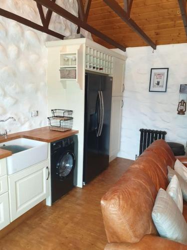 a kitchen with a couch and a black refrigerator at St Patrick's Cottage in Saul