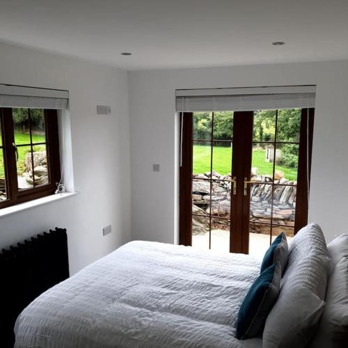 a white bedroom with a bed and windows at St Patrick's Cottage in Saul