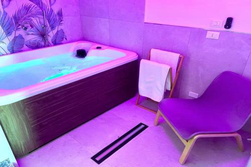 Baño púrpura con bañera y silla en Gelsomino Sea View Suite & Spa en San Vito lo Capo