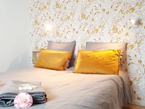 a bedroom with a bed with yellow pillows and a wallpaper at Le Doré Rose by Madame Conciergerie in Bruz