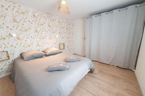 a bedroom with a bed with two pillows on it at Le Doré Rose by Madame Conciergerie in Bruz