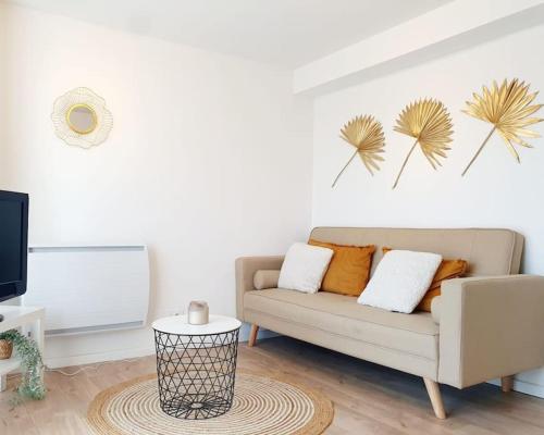 a living room with a couch and a tv at Le Doré Rose by Madame Conciergerie in Bruz