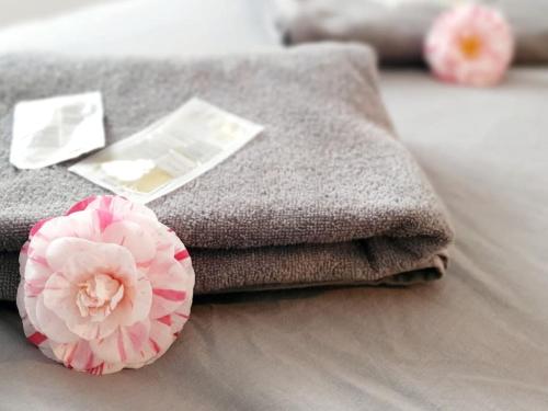 stos ręczników i różowy kwiat na łóżku w obiekcie Le Doré Rose by Madame Conciergerie w mieście Bruz