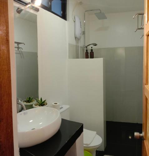 a bathroom with a white sink and a toilet at Corong Beach Resort in El Nido