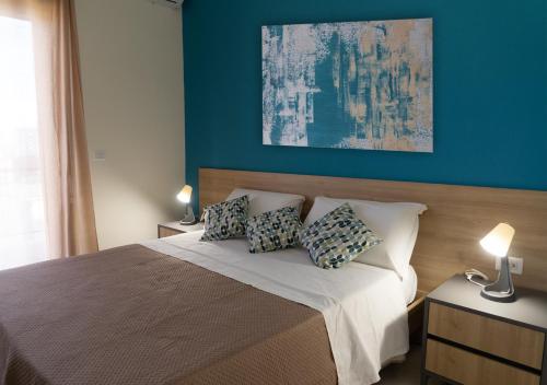 a bedroom with a bed with blue walls and two lamps at PAPALi 289 in Catania