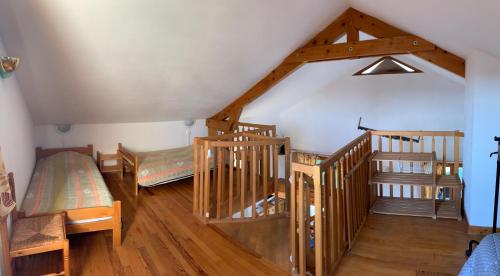 ランゴーニュにあるLac de Naussacの木製の階段とベッドが備わる屋根裏部屋