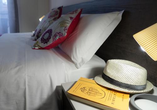a hat sitting on top of a bed with a book at PAPALi 289 in Catania
