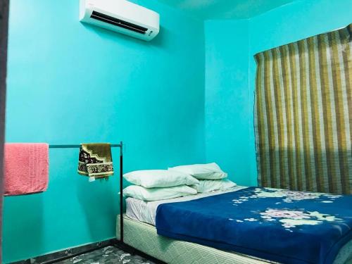 ein Schlafzimmer mit einer blauen Wand und einem Bett in der Unterkunft Homestay/Bilik Teluk Gading in Kuala Rompin