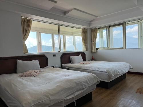 two beds in a room with windows at Bokelai B&B in Renai