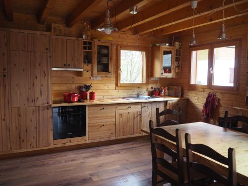 una cocina con armarios de madera y una mesa en una cabaña en LATITUDE 47, en Châtel