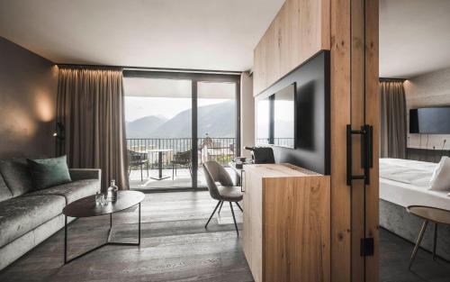 um quarto de hotel com uma cama e um sofá em SomVita Suites em Tirolo