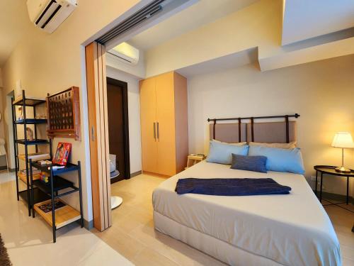 1 dormitorio con 1 cama grande con almohadas azules en Cozy Minimalist Unit at BGC Mall Free Parking en Manila