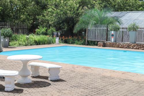 a swimming pool with two white benches next to it at Lodge Laske Nakke in Lydenburg