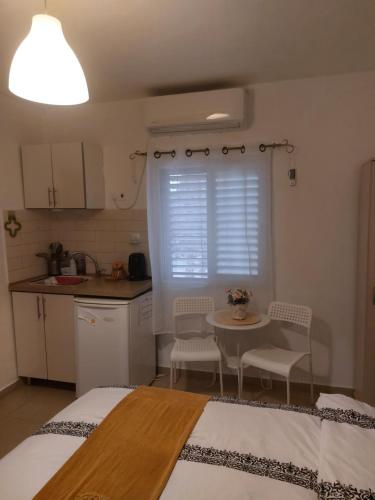 a room with two beds and a table and a kitchen at הצימר של כרמית in Neve Zohar