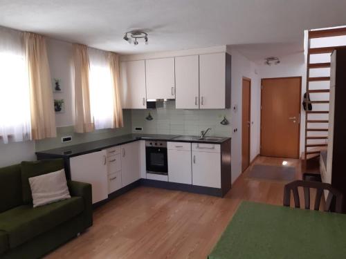 una cocina con armarios blancos y un sofá verde en Raisc - La tua casa in Val Badia, en La Villa