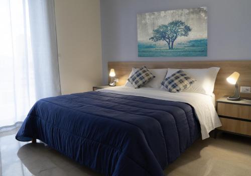 a bedroom with a bed with a blue blanket and a tree at PAPALi 289 in Catania