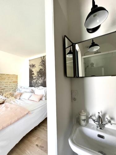 a bedroom with a bed and a sink and a mirror at Gîte Le Domaine Des Faluns in Le Quiou