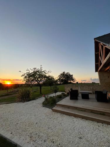 a patio with a bench and a sunset in the background at Gîte Le Domaine Des Faluns in Le Quiou