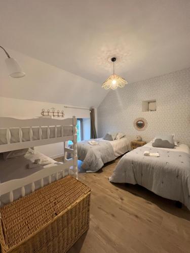 a bedroom with two beds and a chandelier at Gîte Le Domaine Des Faluns in Le Quiou