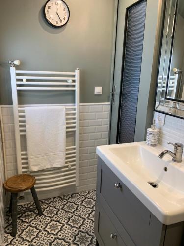 La salle de bains est pourvue d'un lavabo et d'une horloge murale. dans l'établissement La maison Cattleya, au Mans