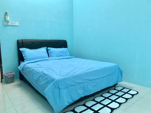 a blue bedroom with a bed with a blue wall at Homestay 69 in Hutan Melintang