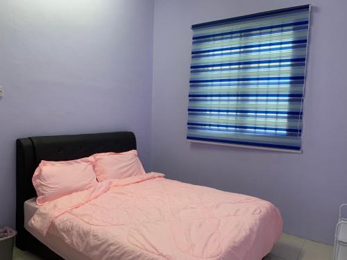 a bedroom with a bed with pink sheets and a window at Homestay 69 in Hutan Melintang