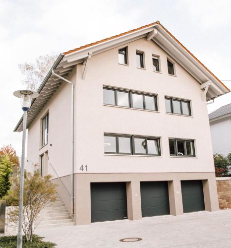 a white house with two garage at Blumen(t)raum - Ferienwohnung in Karlsruhe in Karlsruhe